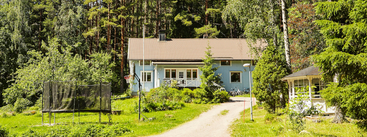 Monikulttuurinen Koti Ilolan vaaleansininen talo ja vehreä pihapiiri.